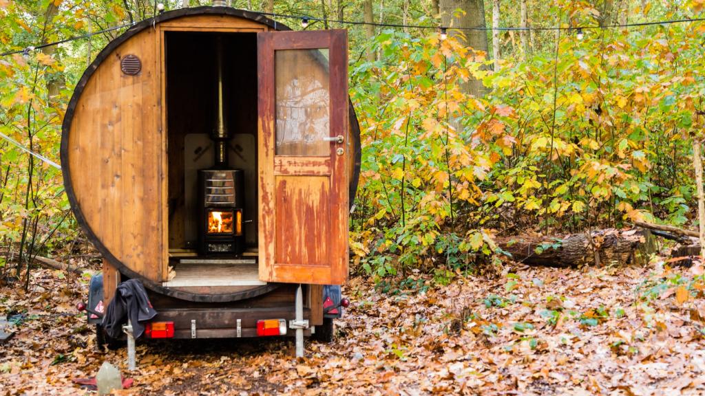 Man sieht eine Fasssauna mitten im Wald