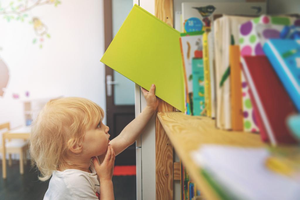 Kind nimmt Buch aus Bücherregal
