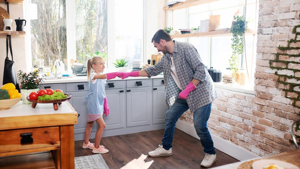 Vater und Tochter mit Gummihandschuhen in der Küche