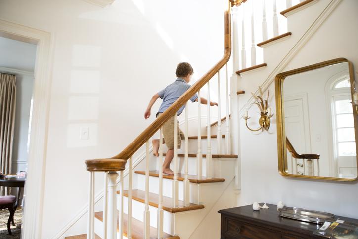 Junge läuft Treppe mit Treppengeländer hinauf
