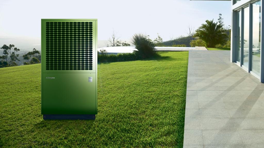 Wärmepumpe auf einer grünen Wiese vor einem Gebäude.