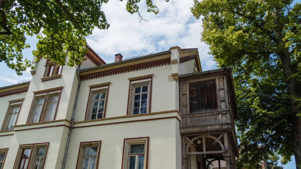 Älteres, repräsentatives Haus mit Holzanbau.