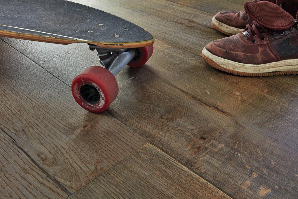 Skateboard und Kinderschuhe auf einem Holzfußboden.