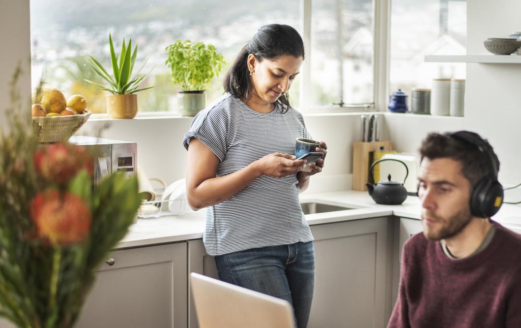Mann, der Homeoffice macht und Frau mit Handy in einer Küche