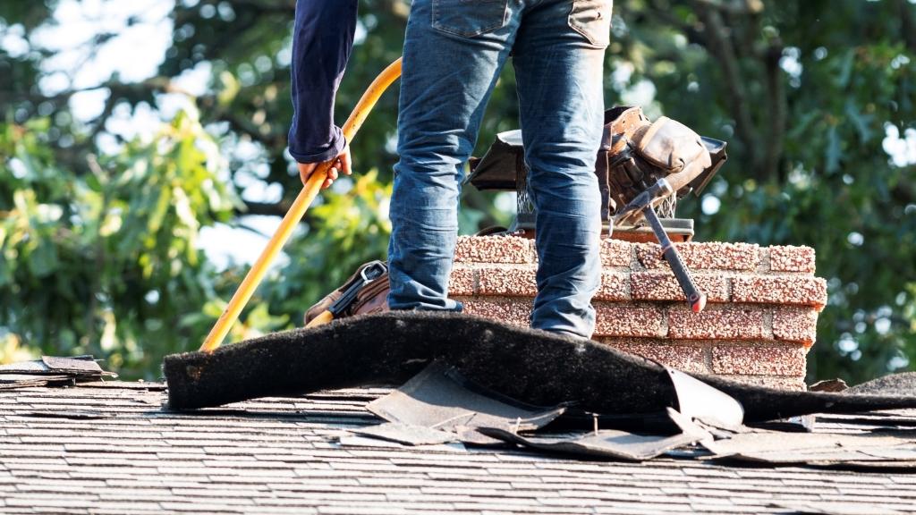 Person entfernt Dachpappe von einem Dach