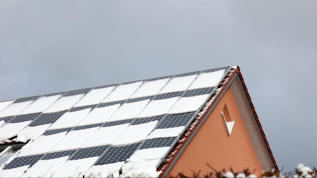 Hausdach mit verschneiten Solarpanelen