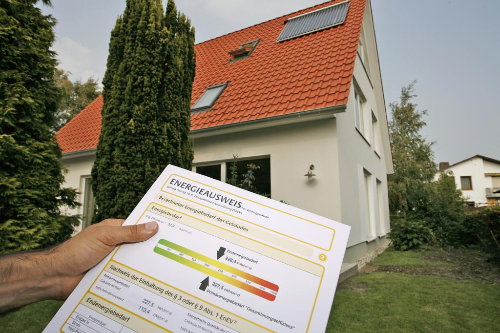 Mann hält im Vordergrund einen Energieausweis in der Hand, im Hintergrund ein Haus.