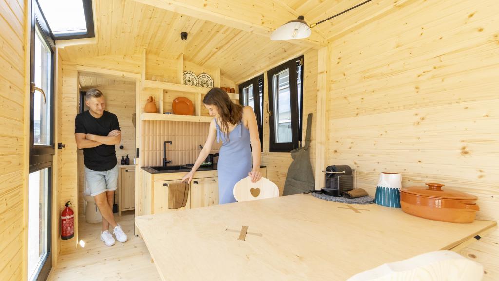Ein junges Paar besichtigt ein Tiny House mit einem Innenraum aus Holz