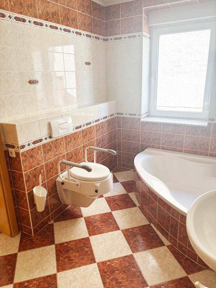 Wannenbadezimmer mit Fenster, Dusche und behindertengerechter Toilette