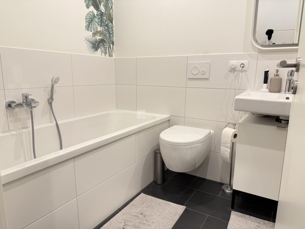Das Badezimmer mit Wanne, Dusche und Waschmaschinenstellplatz